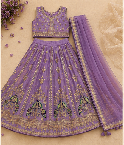A purple and gold embroidered Indian ethnic wear set featuring a sleeveless kurta, a flared lehenga skirt with peacock embroidery, and a matching dupatta, laid flat on a beige background.